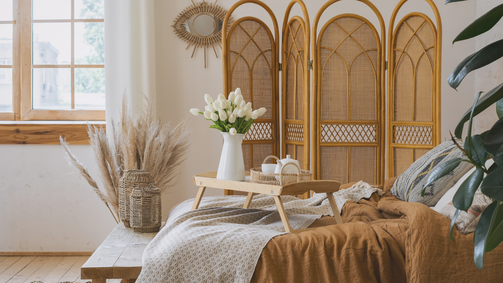 A linen bedroom with cane screen and white tulips