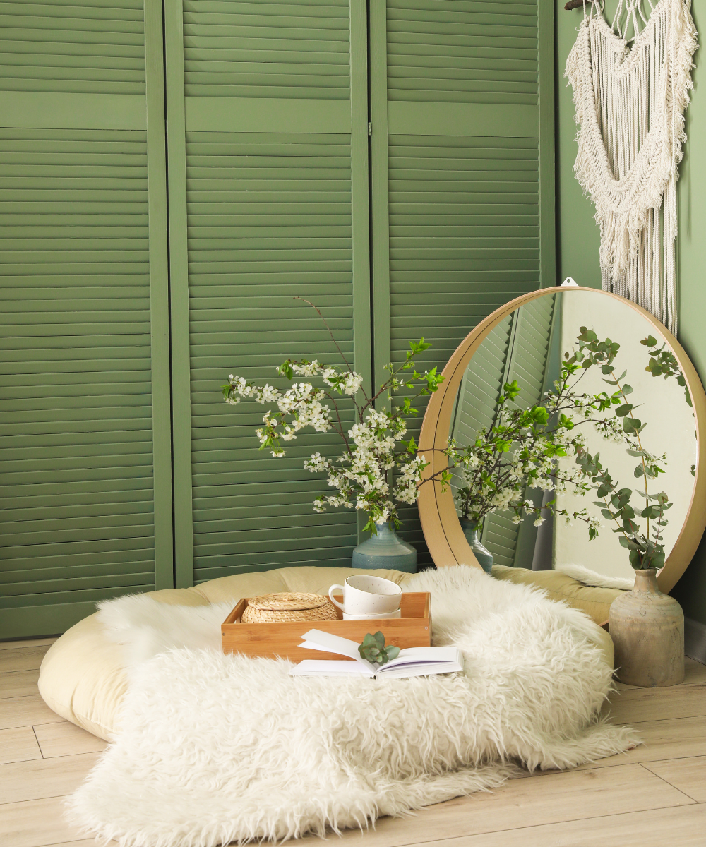 A quiet corner with a round ottoman, mirror and sage shutters